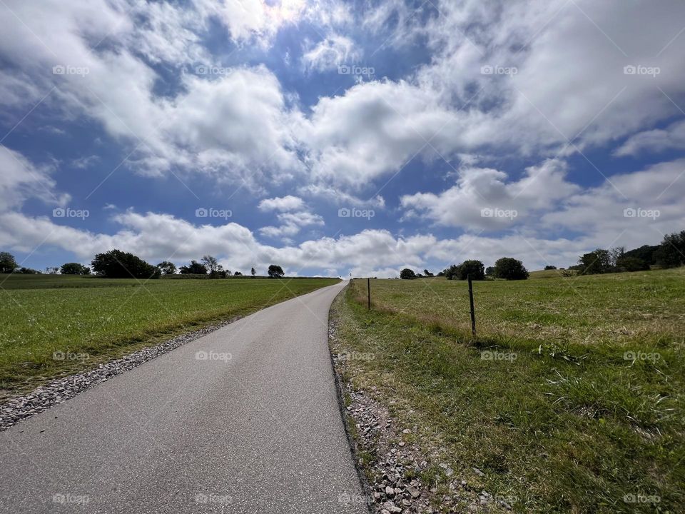  Clouds above the green field and a country road 