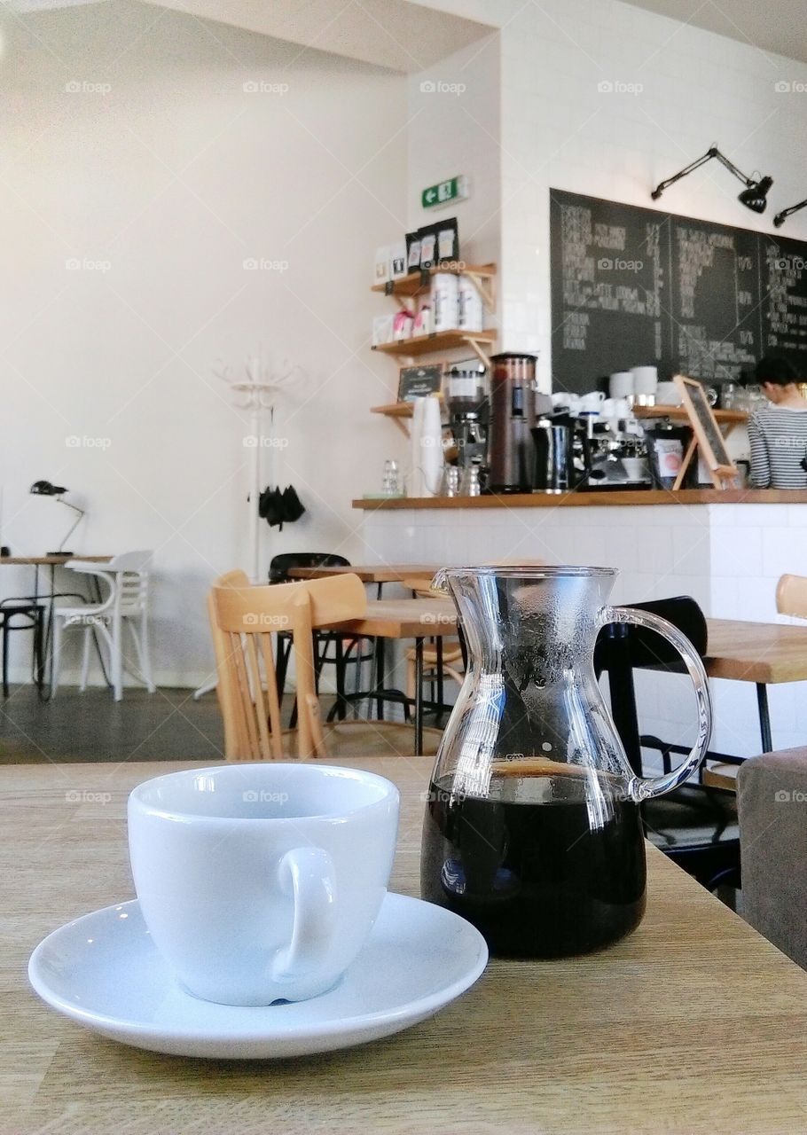 Cup and pot of coffee on a wooden table in cafe