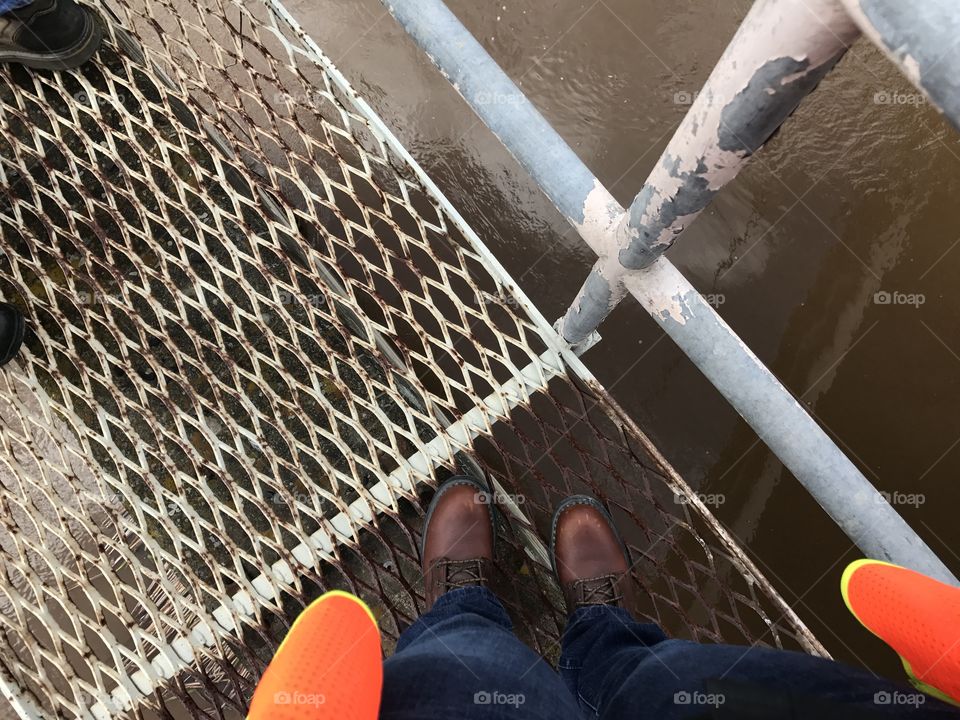 Clean work boots on metal grating over storm water