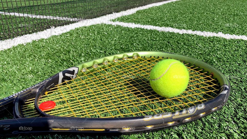 tennis racket and ball on grass court