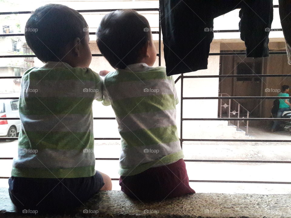 small kids sitting in a balcony and watching outside