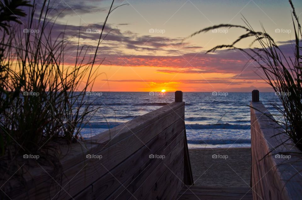 Boardwalk leading towards sea during sunset