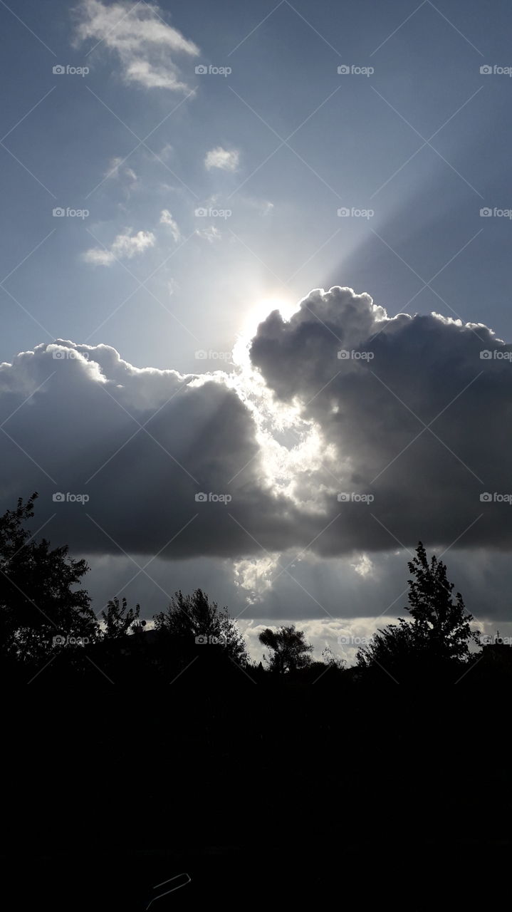 the sun peeks out from behind rainy clouds