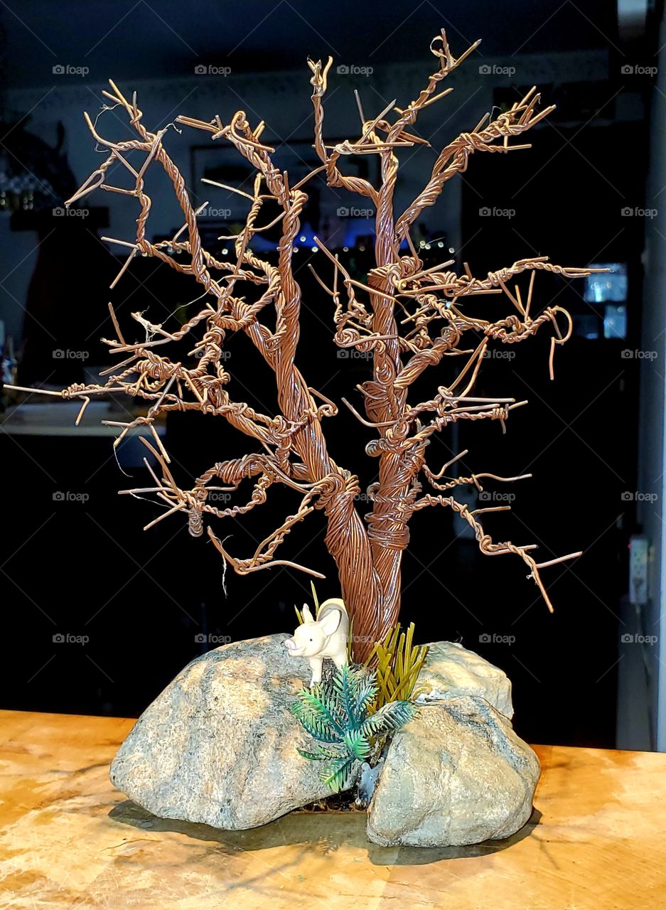 Artistic handmade copper wire bonsai tree twisted into shape. Crafted by hand, it appears to be growing from between rocks.