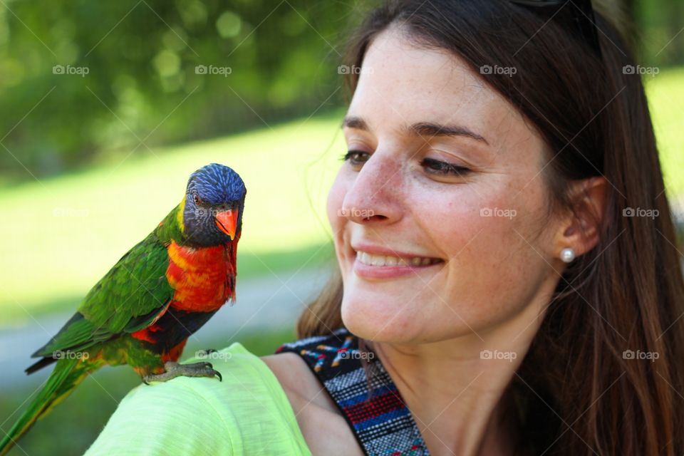 Parrot perching on woman's shoulder