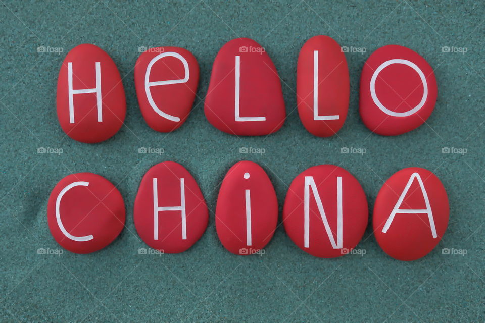 Hello China, creative text composed over green sand with red colored stones