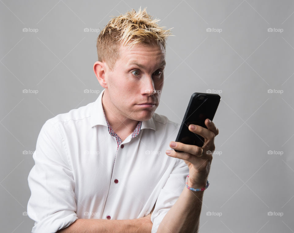 Man with cellular phone acting surprised.