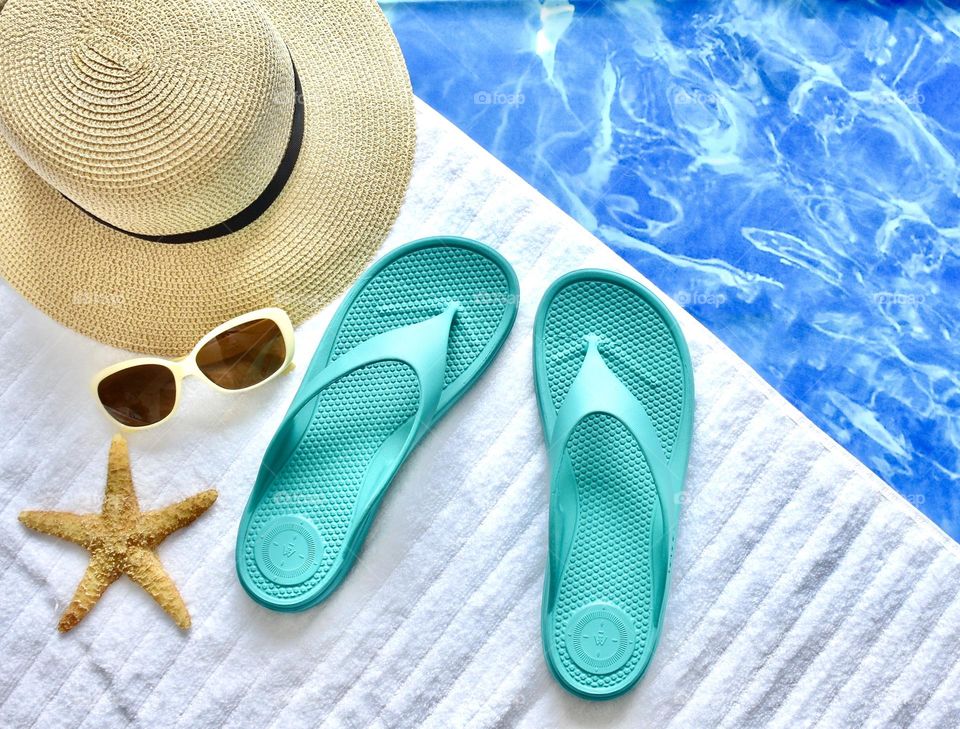 Still life day at the pool, flip flops, sunglasses, hat, towel