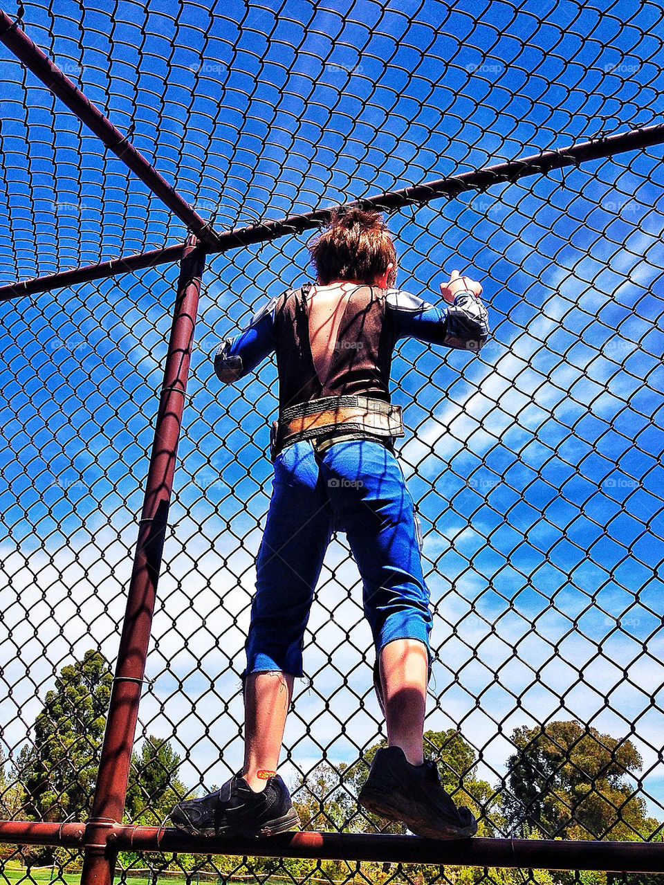 Young boy climbing a chain link fence