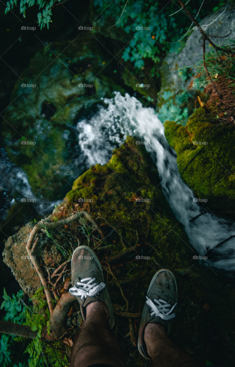 Man standing on top of a waterfall in the forest.