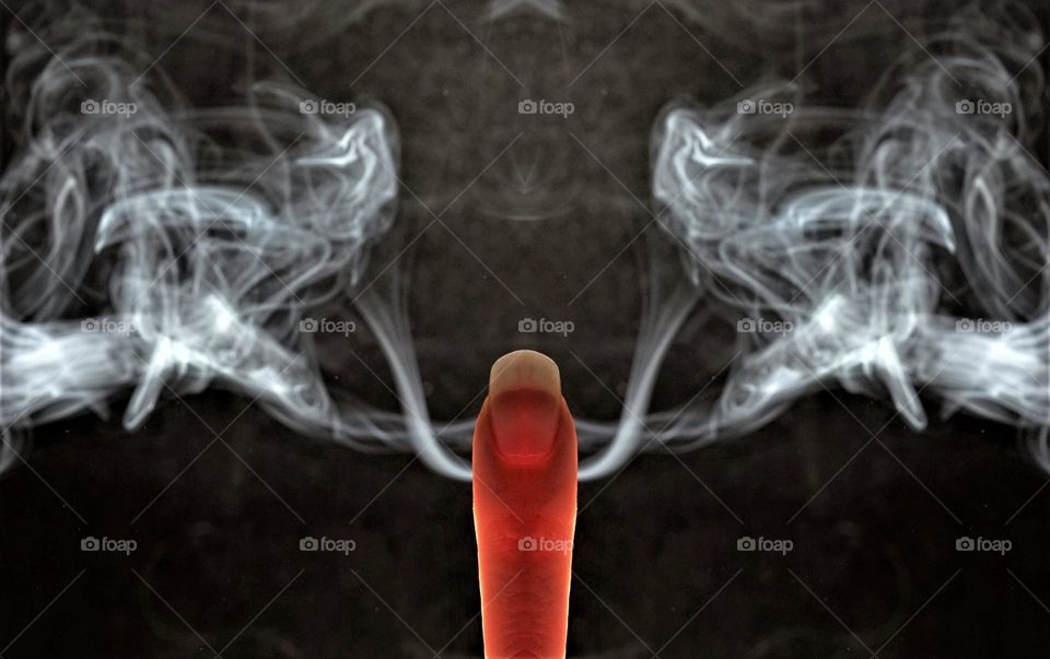 low key  close up image with smoke coming out of a finger in front of a black background