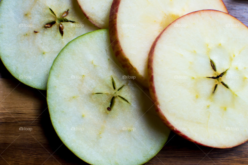 Sliced red and green apples on dark wood