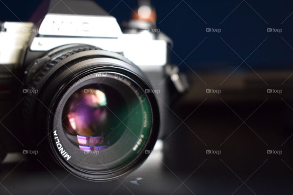 A colorful close up shot of a vintage Minolta film camera lens with blurred background. 