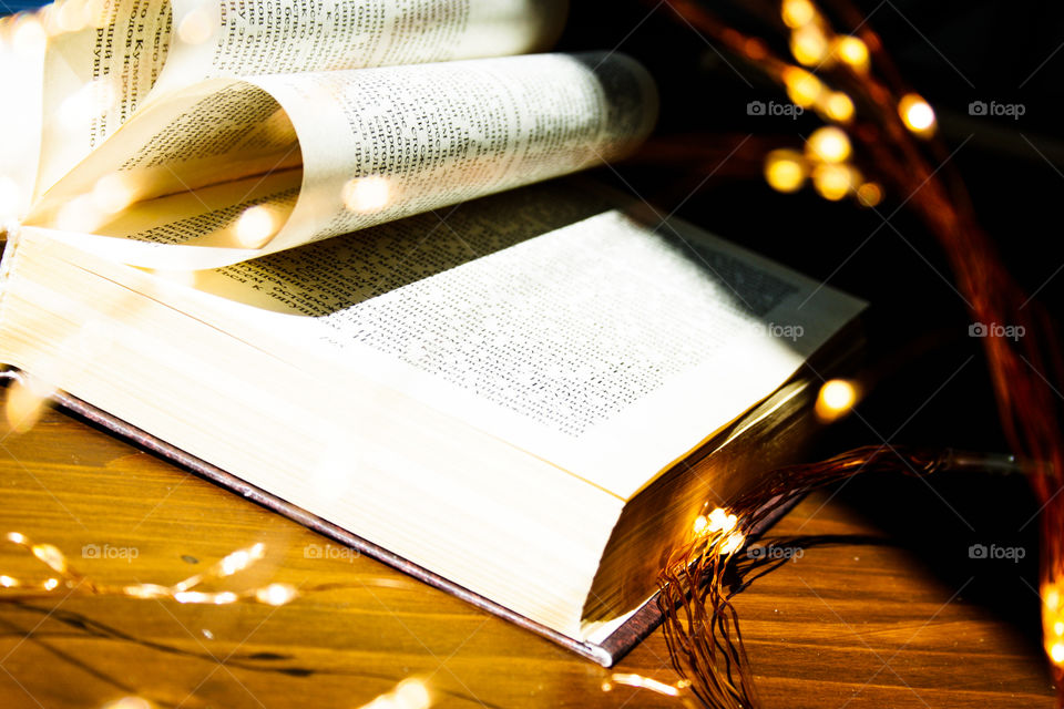 Book and candle light in wood background 