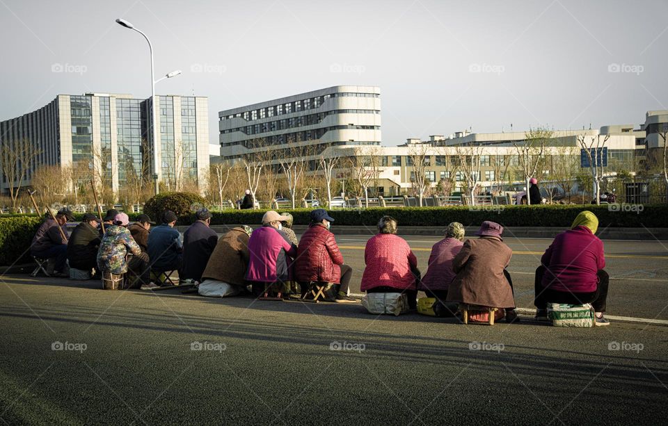 The workers waiting on the road to be hired .