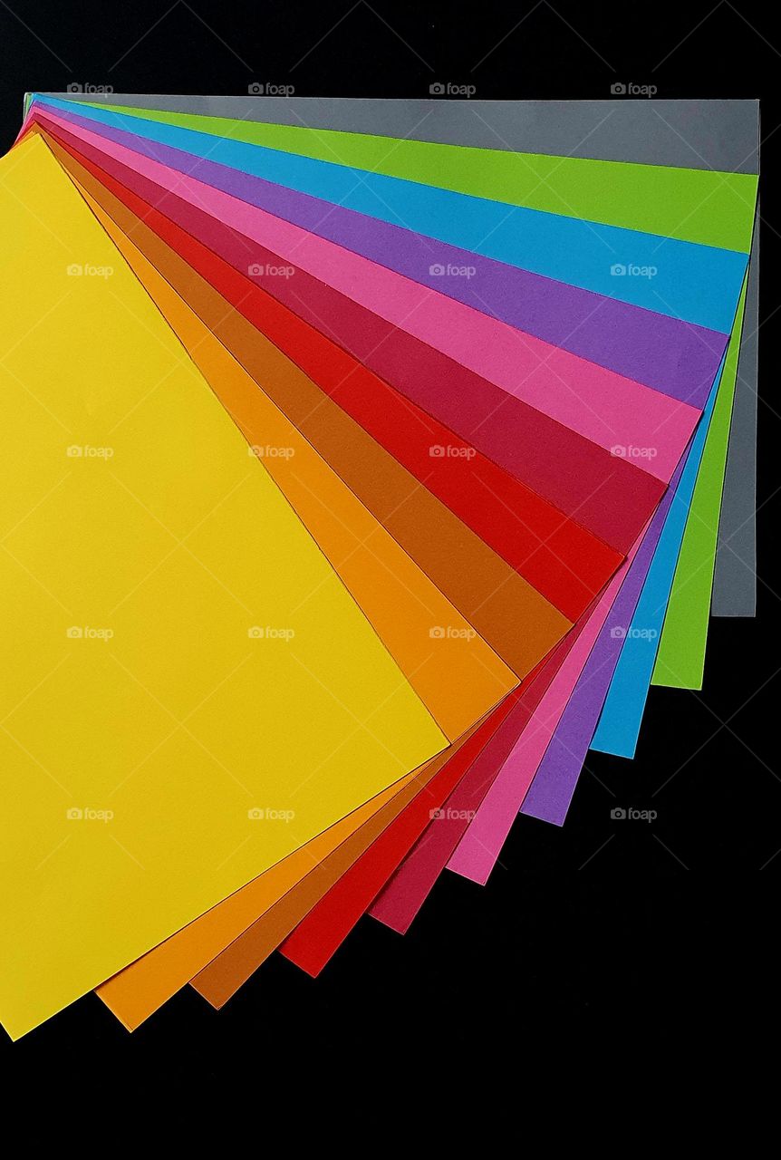Primary colours flatlay composed of a fan-shaped set of colour papers on a black surface