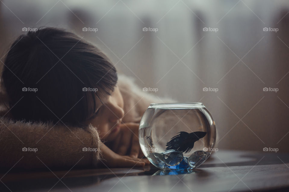 Girl with fish in round aquarium.