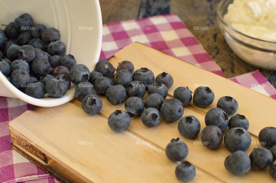 blueberries rolling on a wooden board