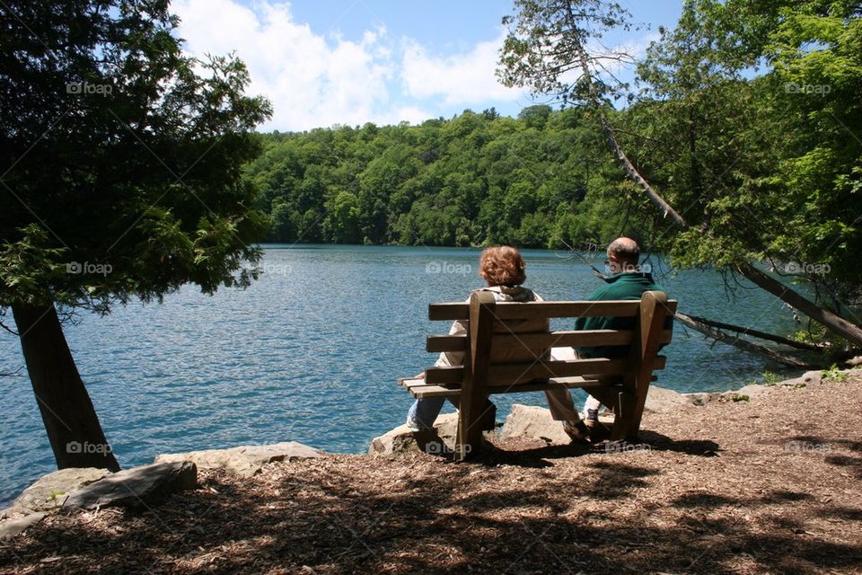 People sitting on bench against river