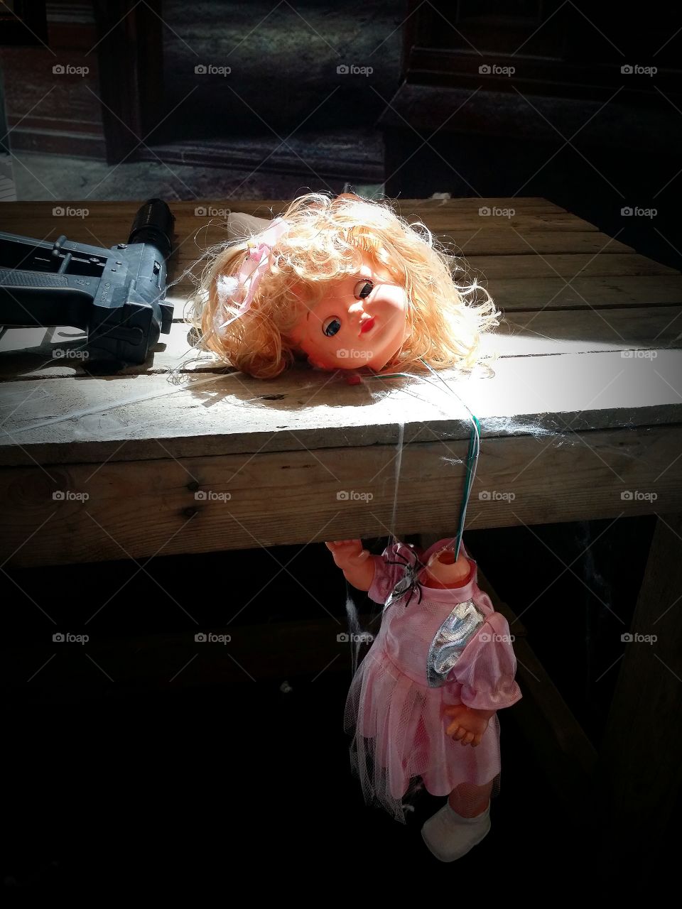 Woman decapitated dolls were placed on a wooden table with a machine gun on Halloween.
