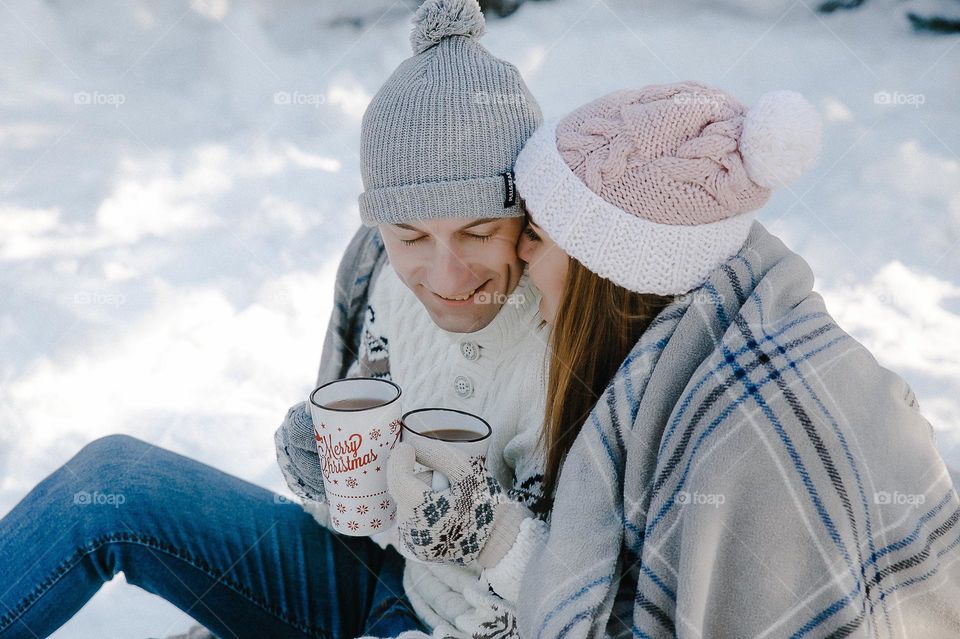 Couple in love drink tea in winter forest