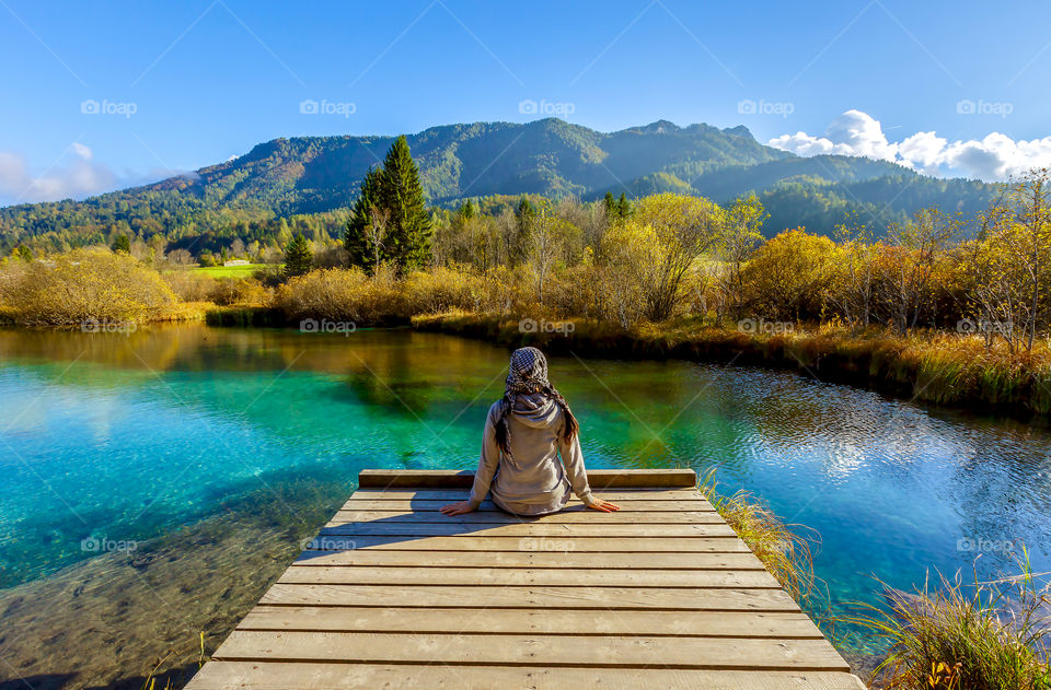 Rear view of a woman sitting on wooden pier