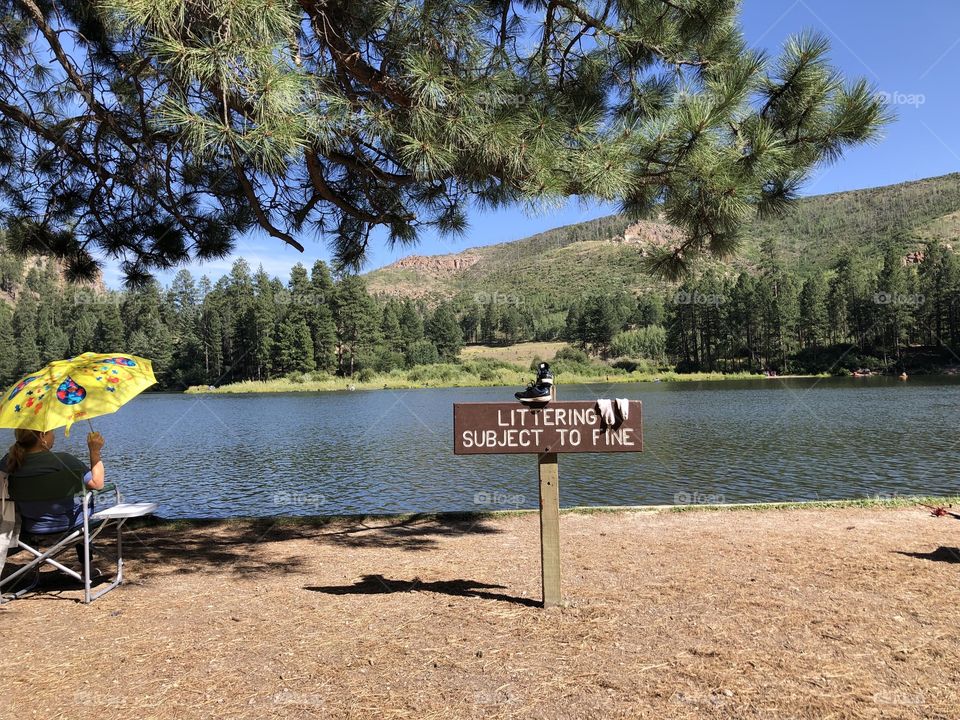 A day by the lake, shade from an umbrella.   Drying your shoes and socks on a sign, which reminds everyone not to litter.     