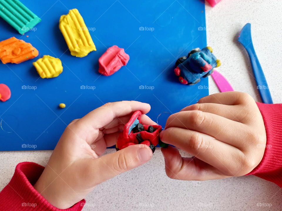 a child sculpts a car from plasticine.