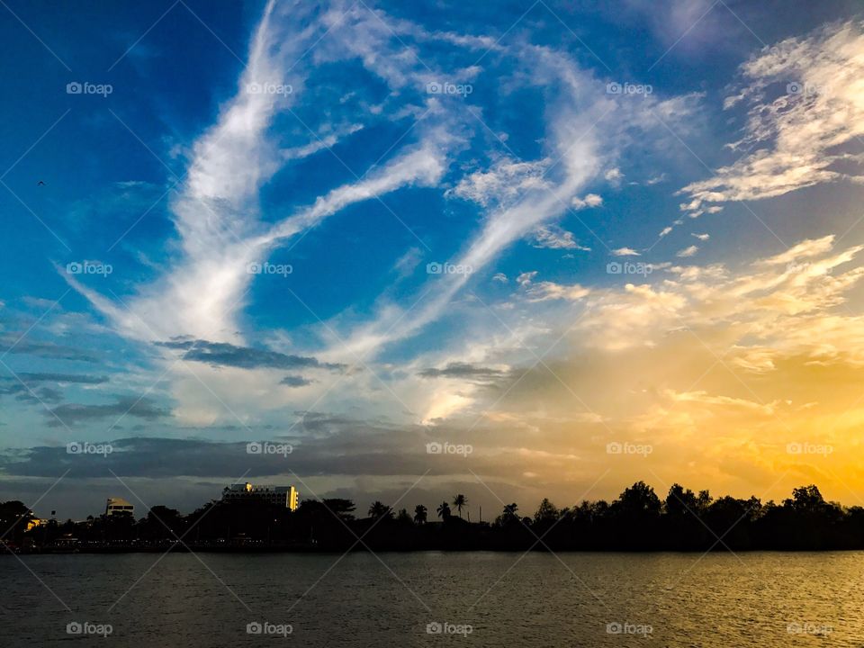 Rolling clouds forming imaginative shapes over river during sunset