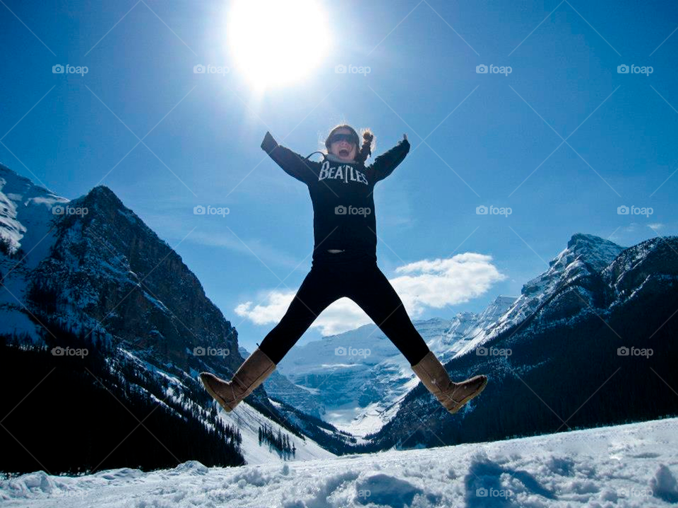 Happy girl jumping in snow with mountains in the background