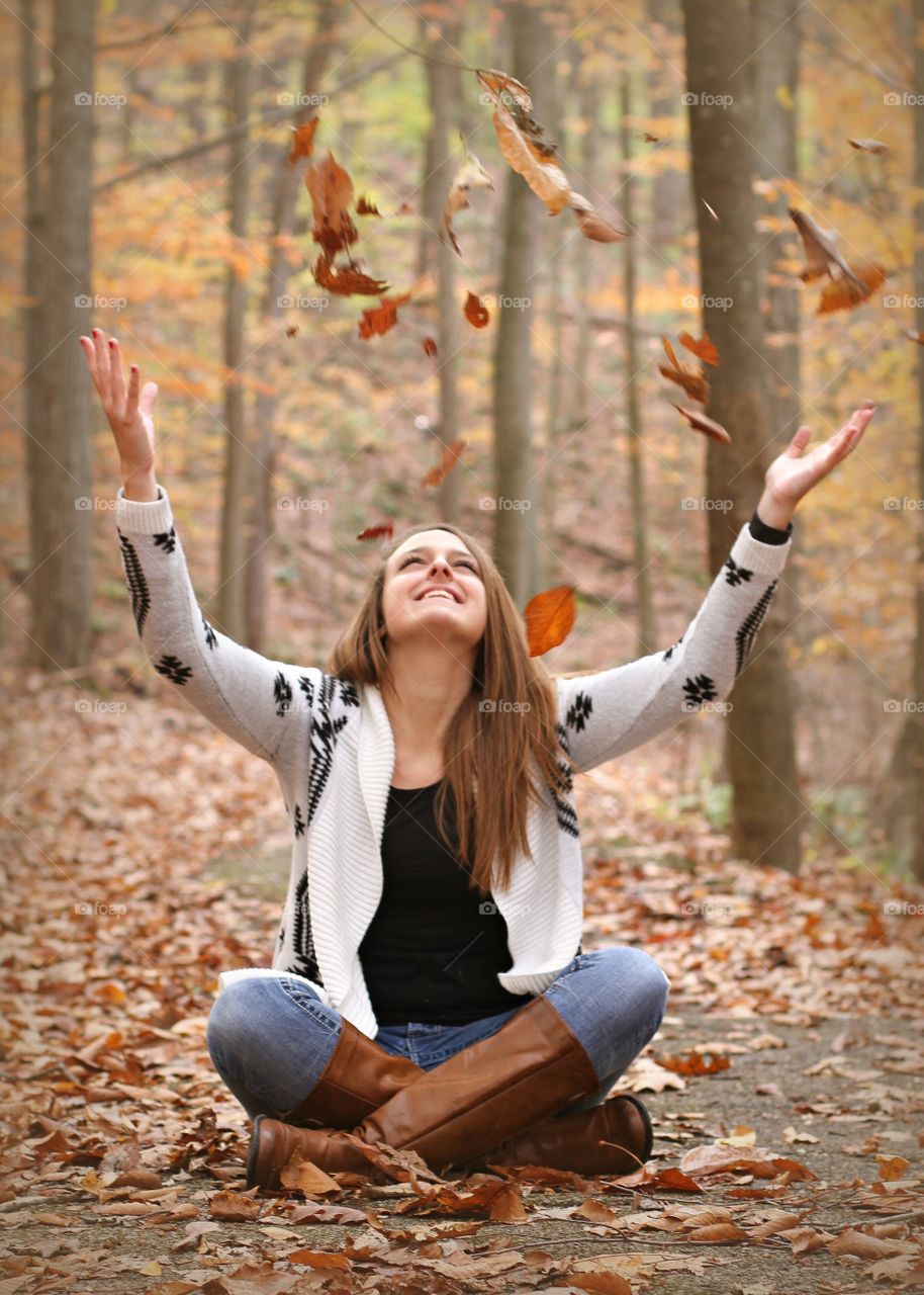 Young woman sitting in autumn leaves