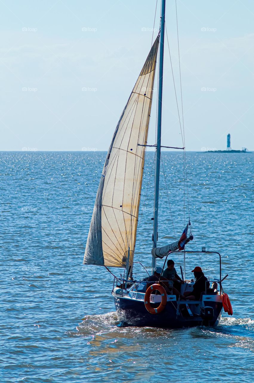 Triangular sailboat near the yacht