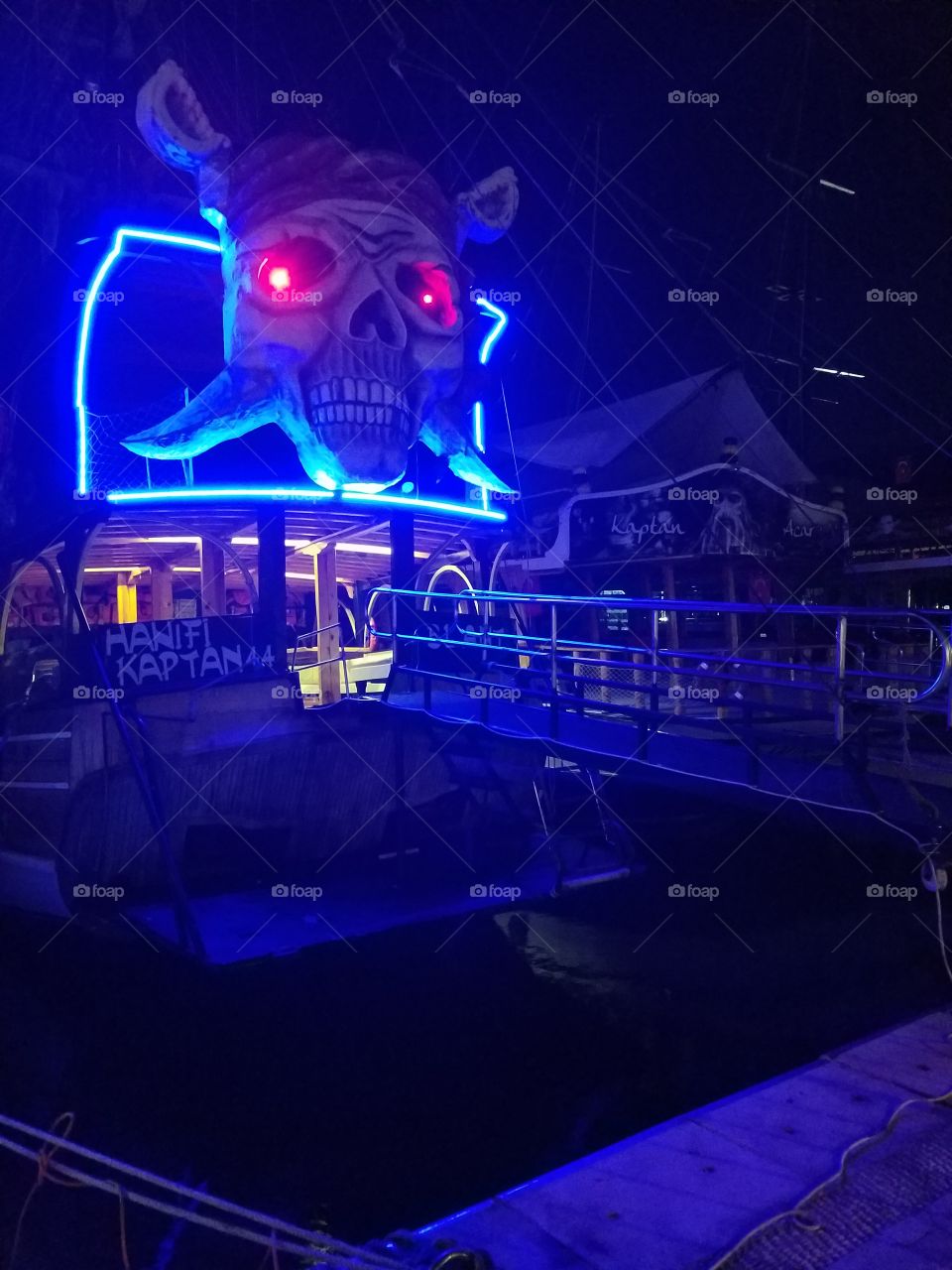 a lit neon skull on the back of a shop in antalya harbor