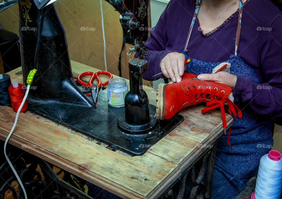 Shoe shop. Female cobbler at work. It repairs the boots.