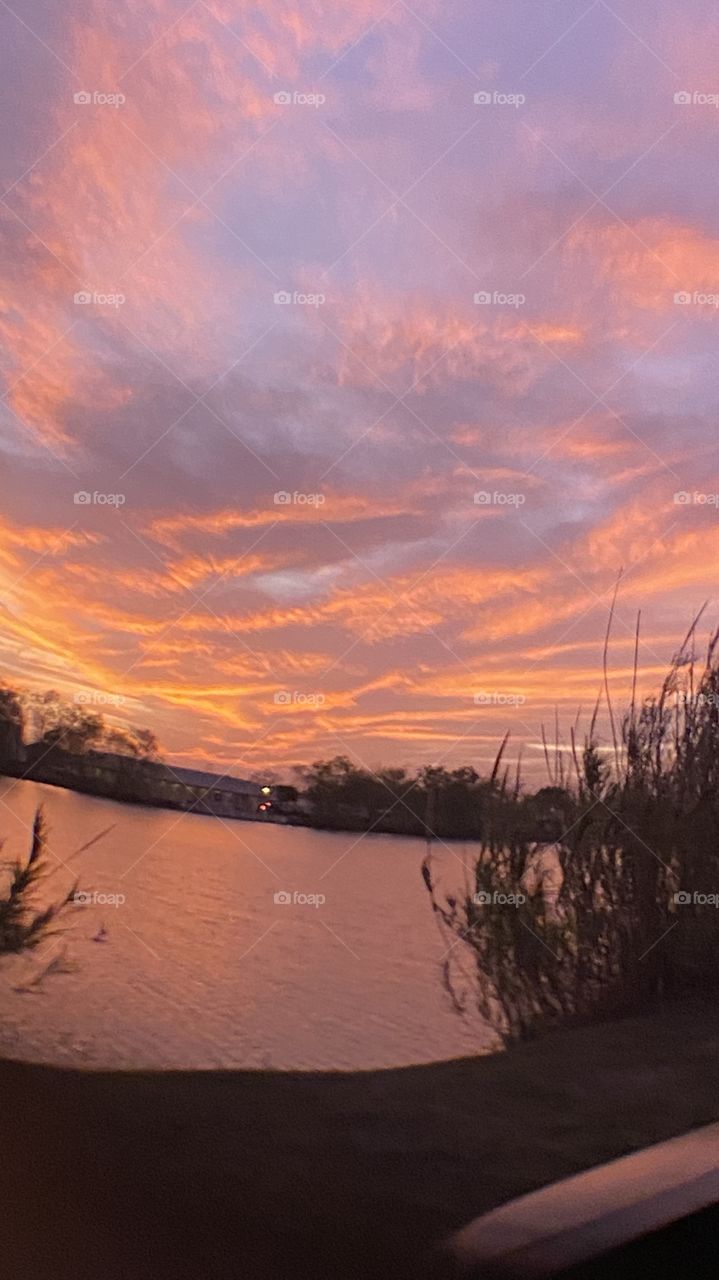 Sundown Completed Sky is opening up. Blistering Orange Slivers along with Yellows upper atmosphere bleeding down to the lower with Grays Blues Violets tops of high clouds getting into the act by opening up.