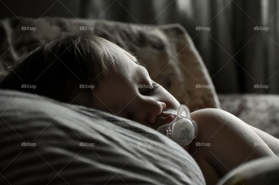 Cute 19 month toddler boy sleeping on his mother's chest 
