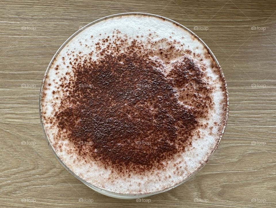 Cappuccino with powdered cocoa in a glass cup