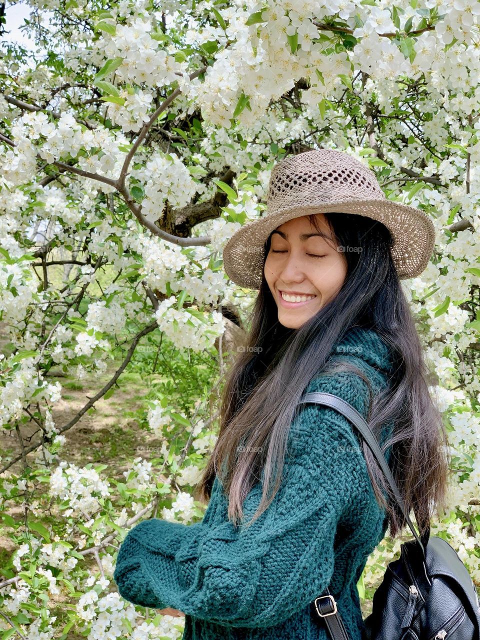 The smile of the woman wearing a hat, with long hair and the eyes closed.