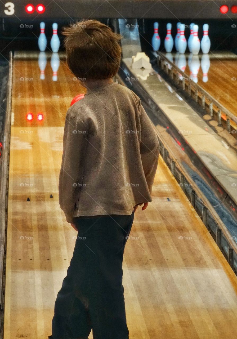 Hoping For A Strike At The Bowling Alley. Young Boy At The Bowling Alley