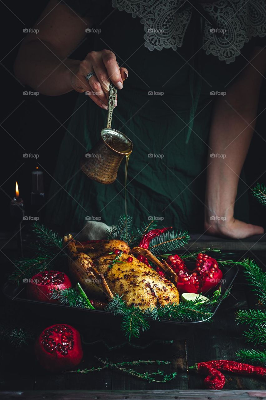 Christmas turkey dinner. Baked turkey garnished with red berries of pomegranate and spruce brunches in front of burning candles