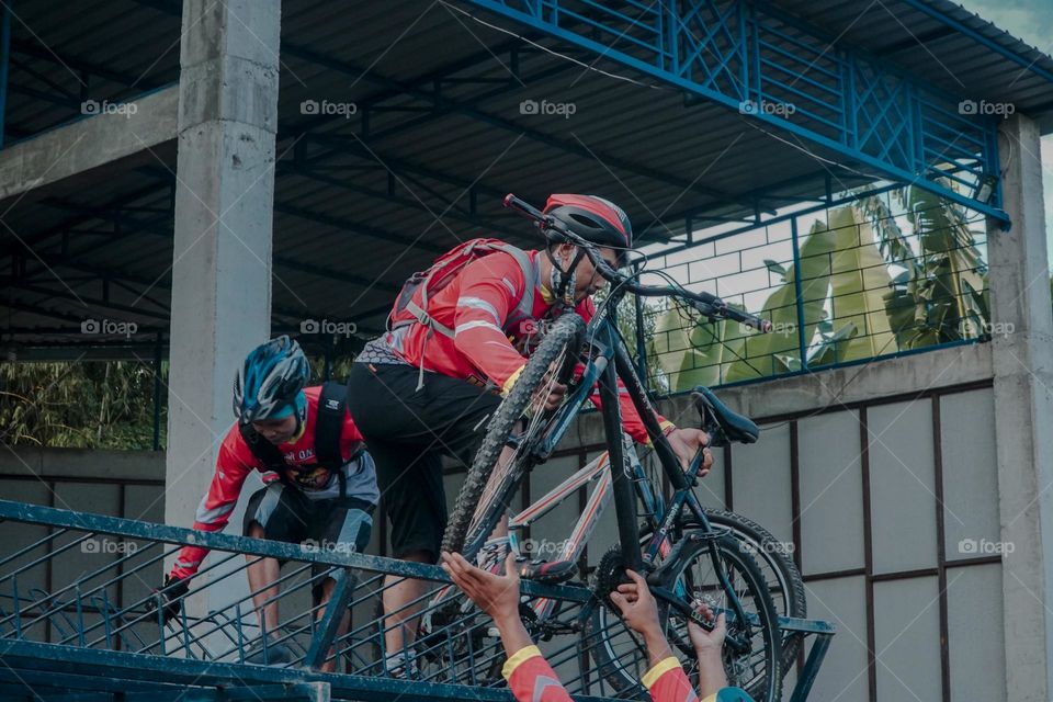Mountain cyclist unloading bicycle from transport vehicle.