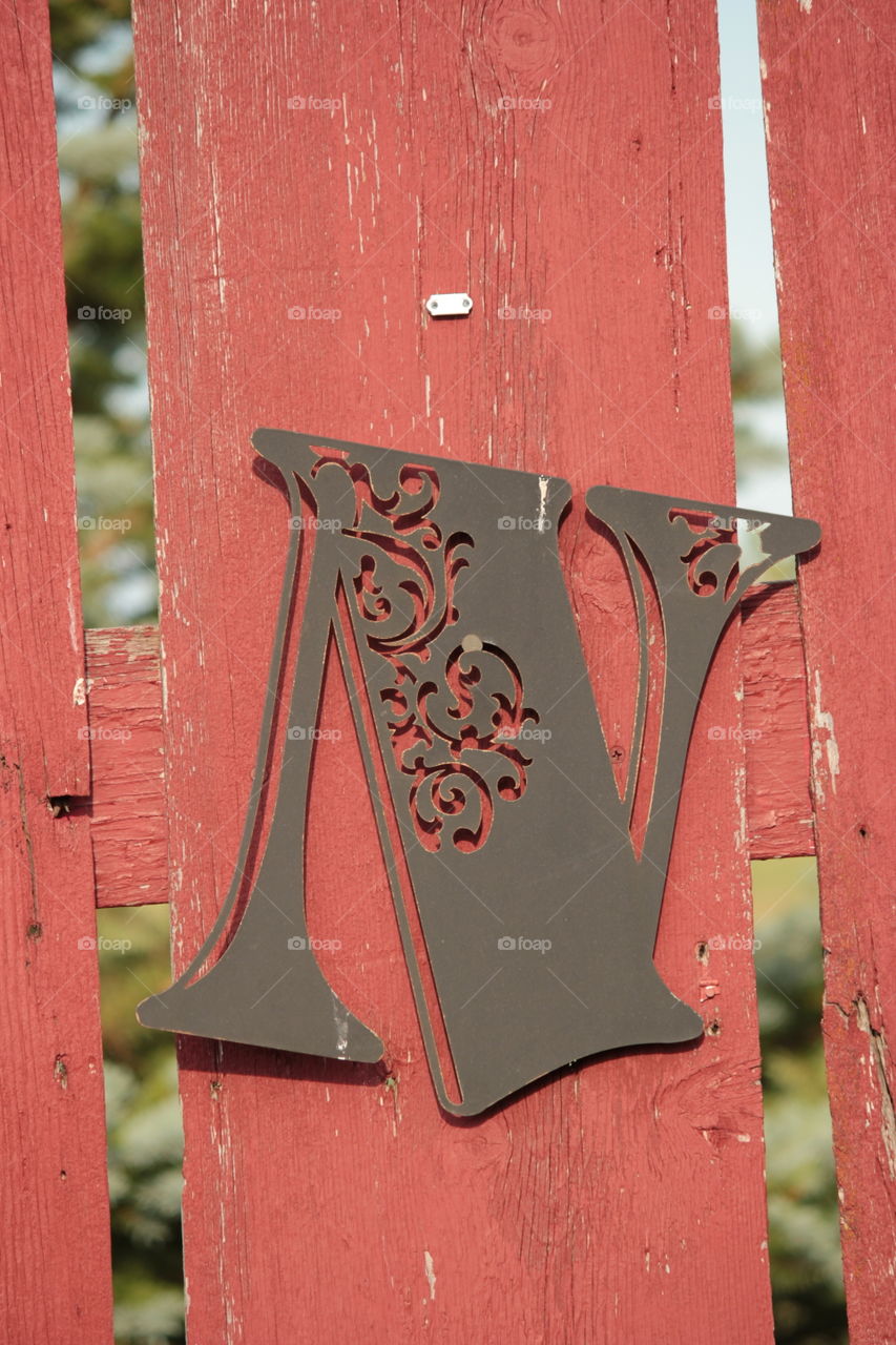 Decorative N on old red wooden fence