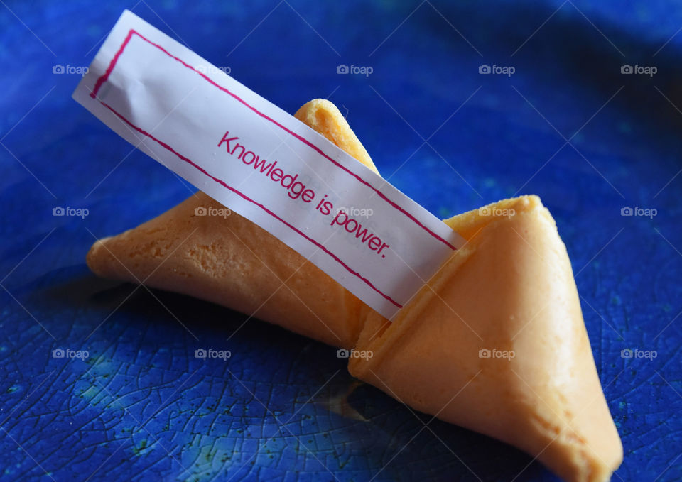 Fortune cookie with fortune on a blue plate