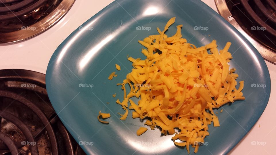 shredded cheese on teal plate in the kitchen