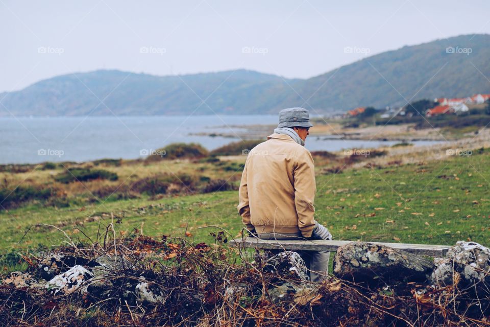 Elderly man sitting outdoors by the coast