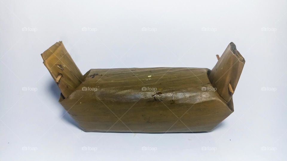 Lontong or boiled rice wrapped in banana leaves on an isolated white background in eye level view