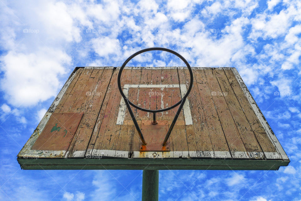 Old street basketball ring against the sky. Old wooden basketball shield against the blue sky