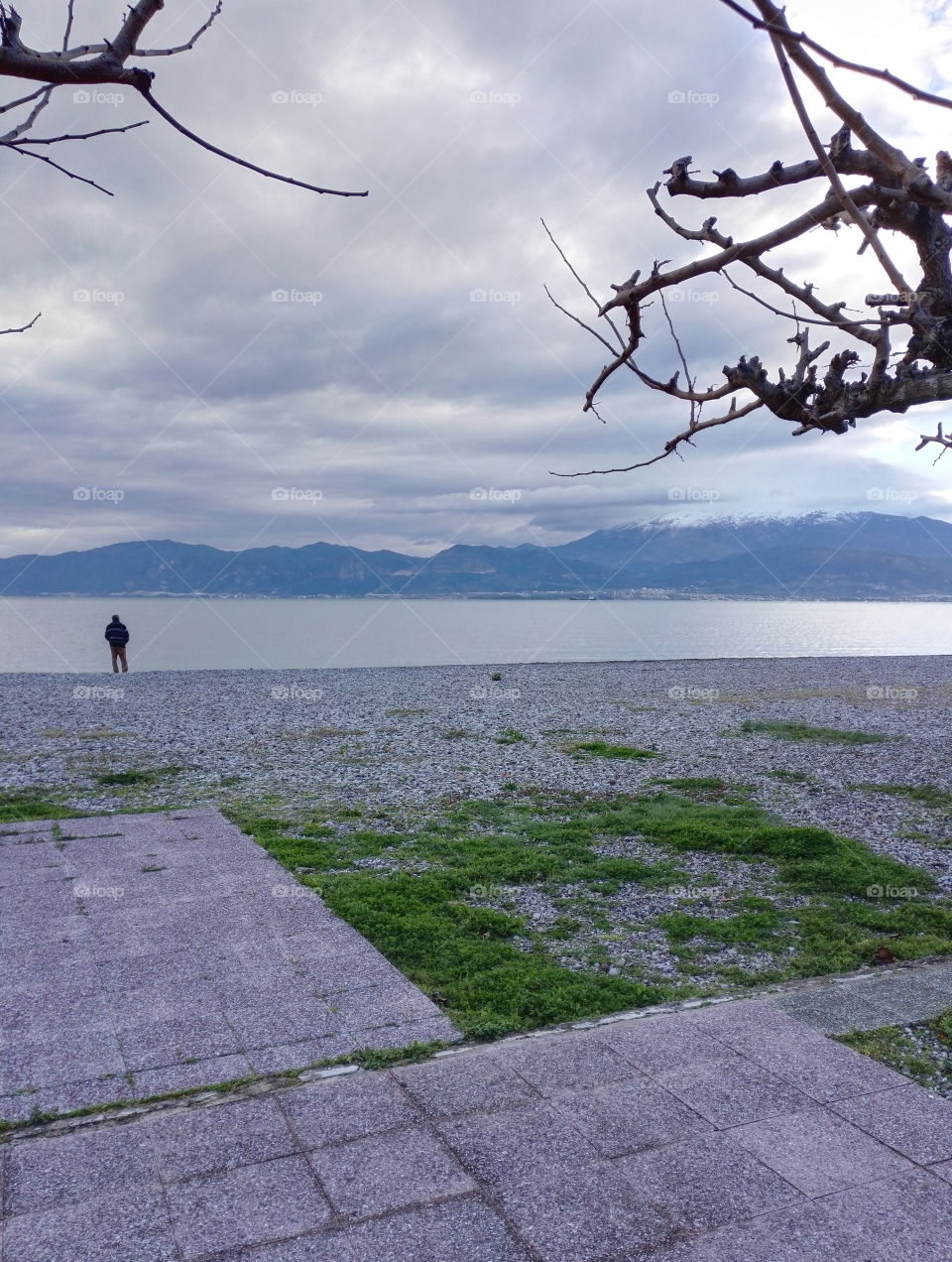 man standing on the beach looking to the mountains in the morning