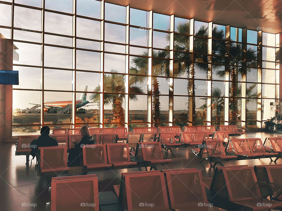 Two people watching through the window and waiting for a plane to travel 