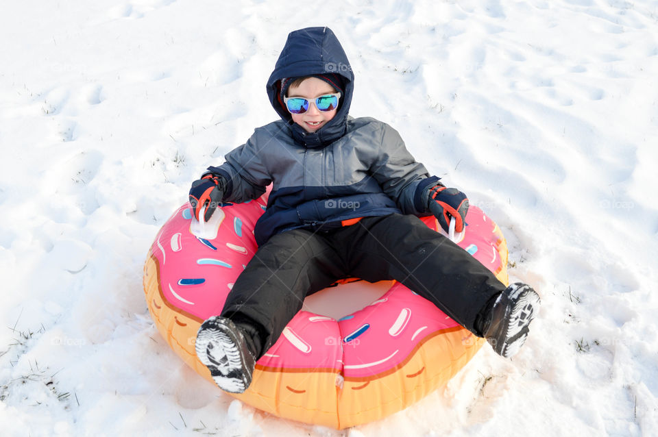 Young boy happily riding a snow tube